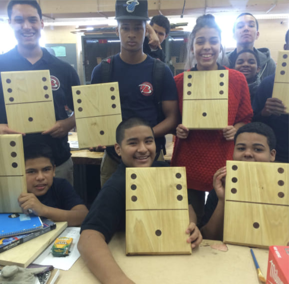 Students displaying oversized wooden dice they built in class