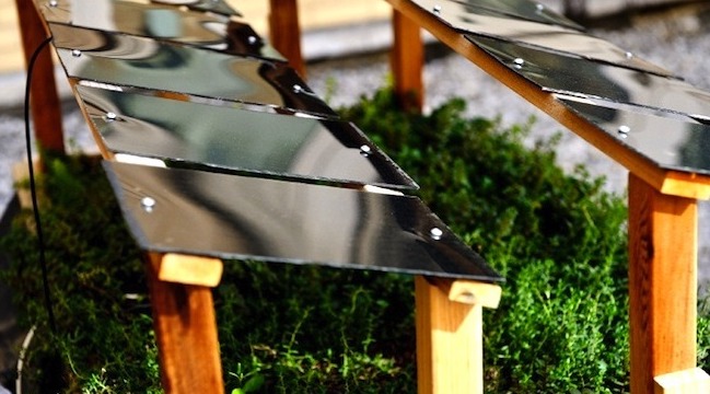 Small solar panels on wooden frames surrounded by green moss