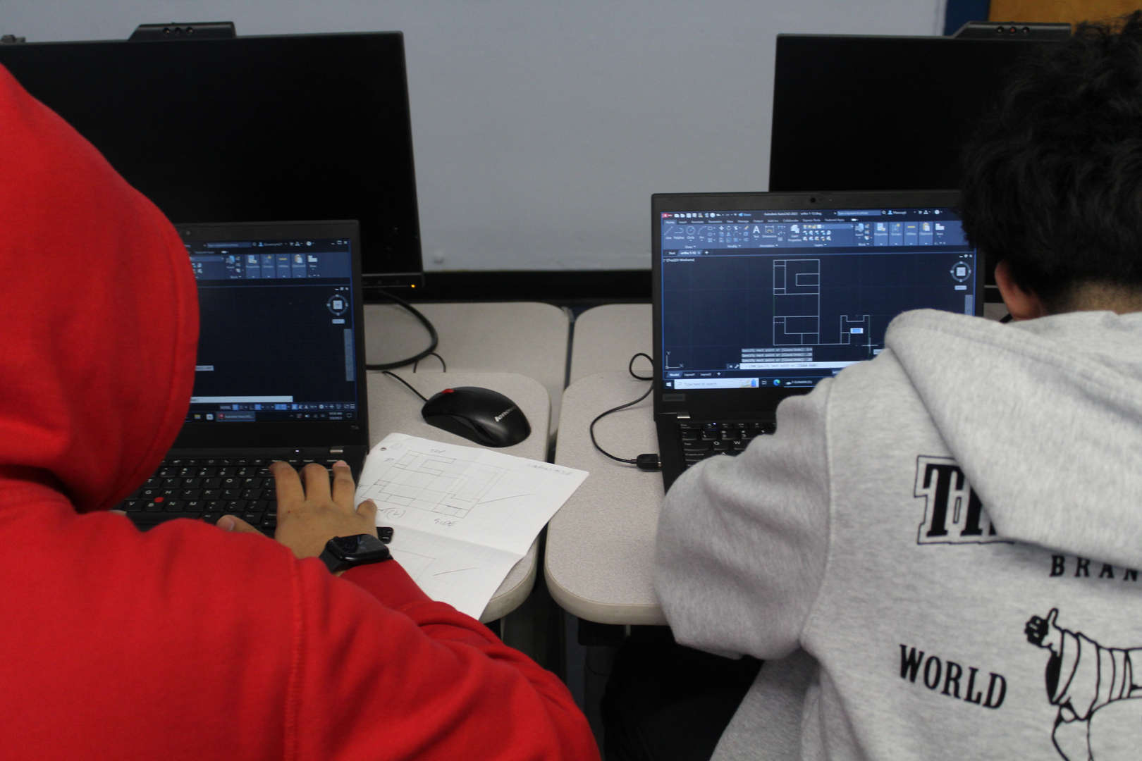 Two students using CAD software on laptops in design class
