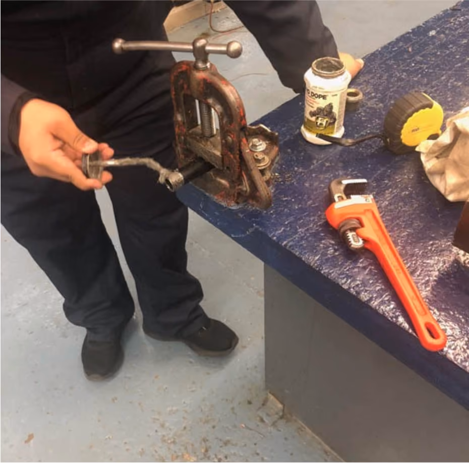 Student using pipe vise and plumbing tools during vocational training
