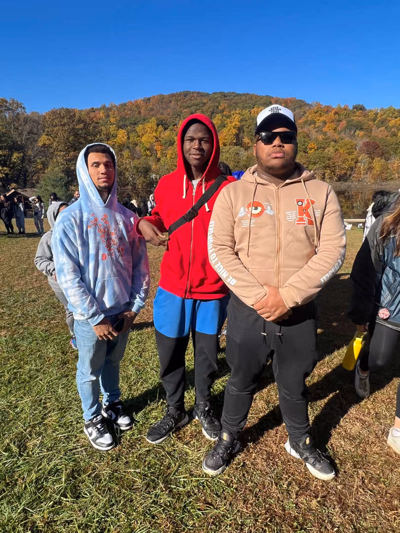 Three students posing outdoors at fall school event
