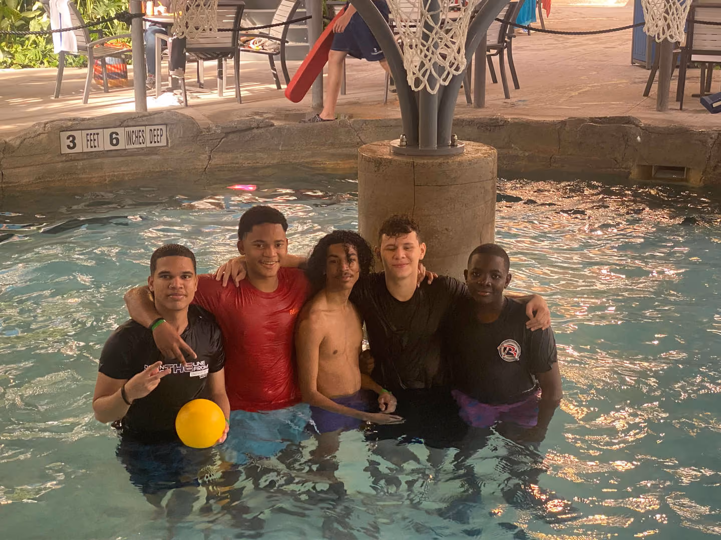 Five students posing together in a swimming pool during a school trip