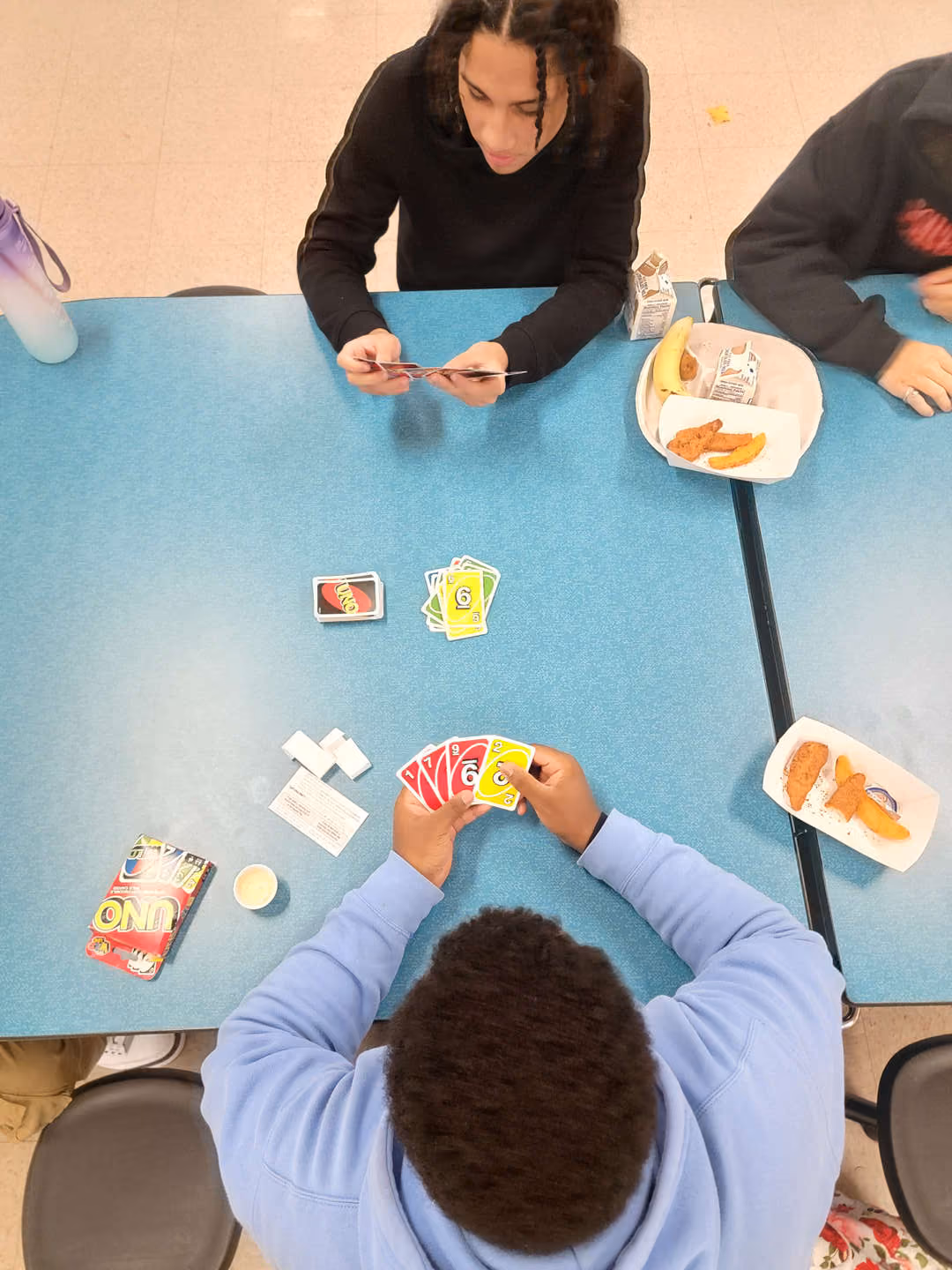 Students playing Uno card game during school lunch