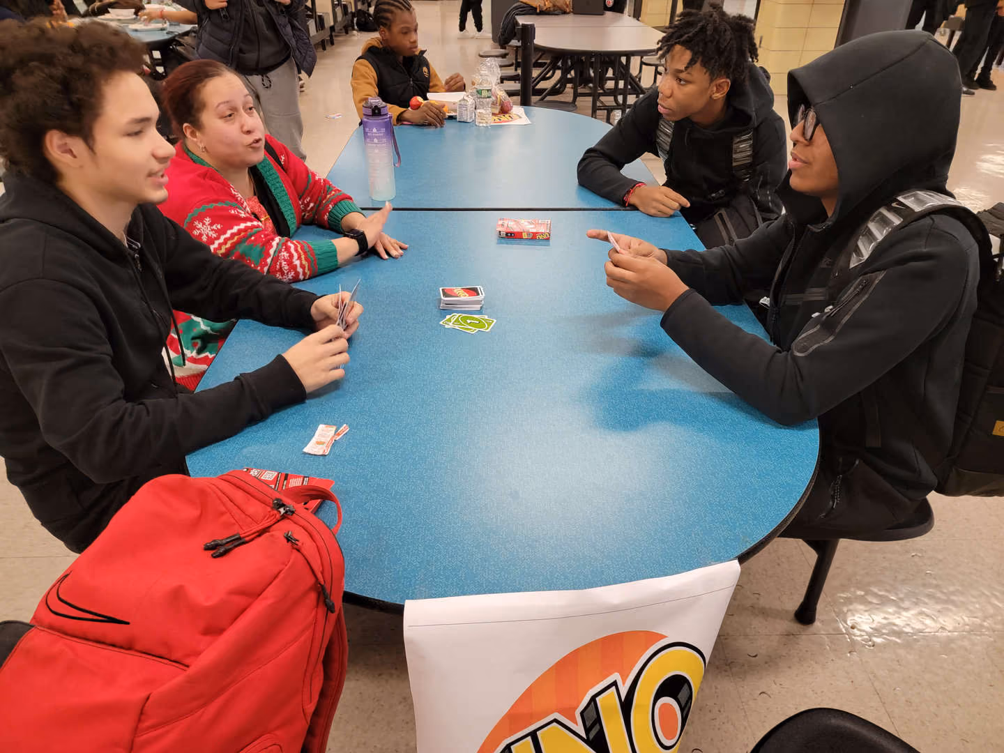 Students playing Uno card game together in school cafeteria