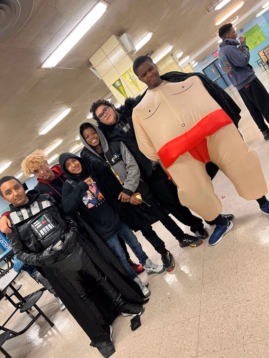 Students in Halloween costumes pose together in school cafeteria