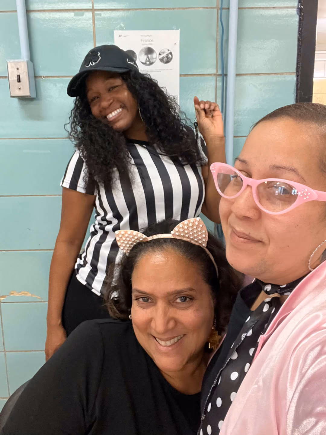 Three staff members smiling in costume during a school spirit event