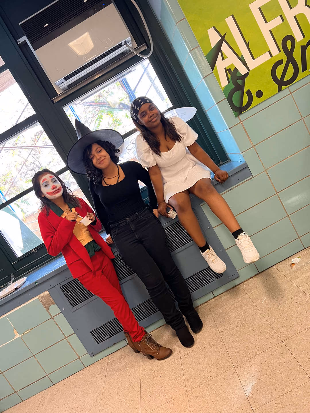 Three students in Halloween costumes at school hallway
