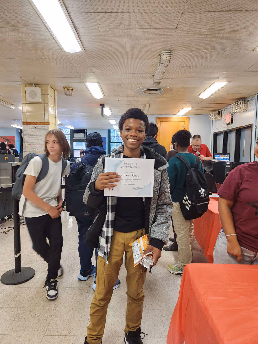 Student smiling while holding a perfect attendance certificate