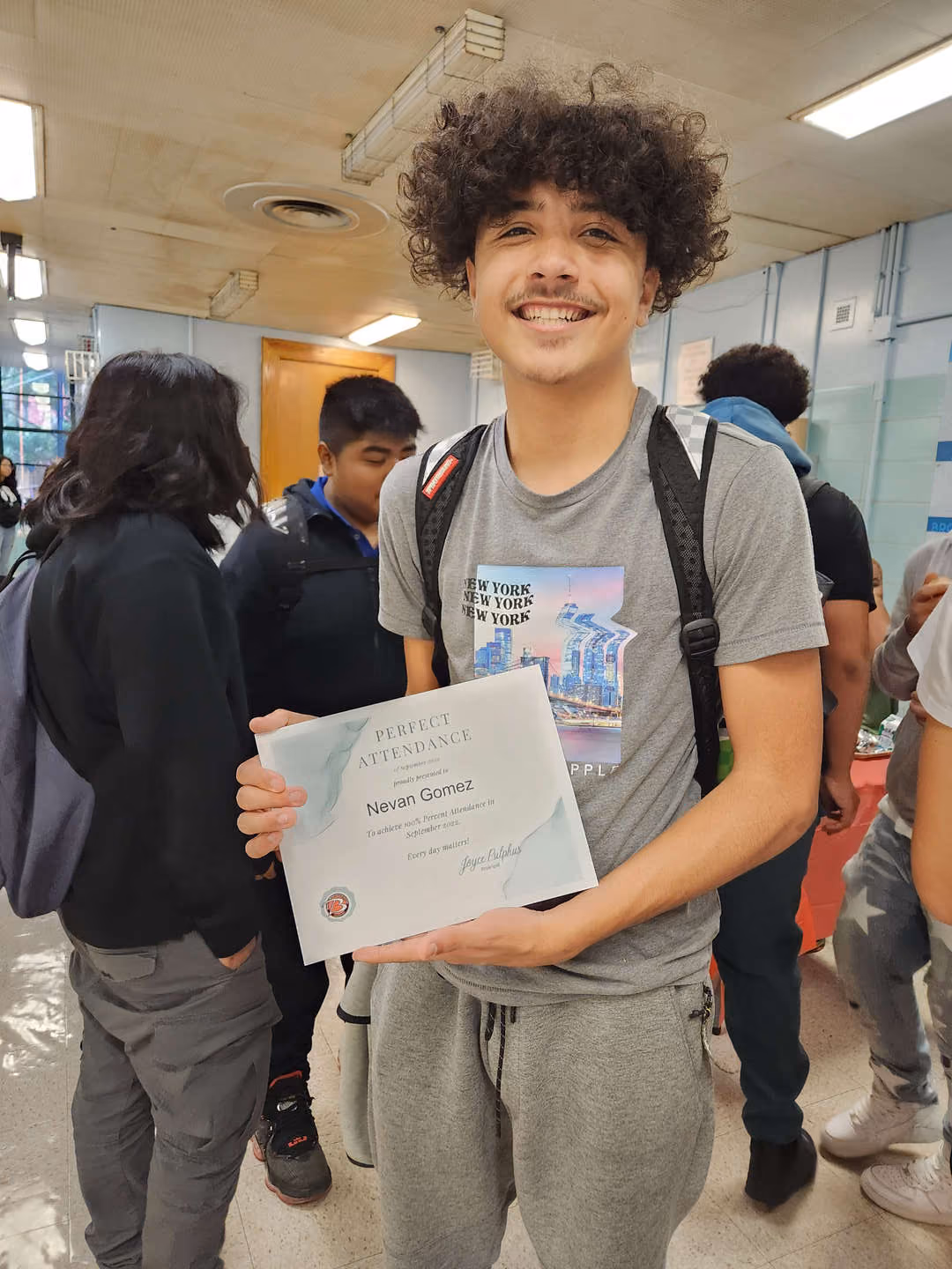 Student Nevan Gomez smiling and holding perfect attendance certificate