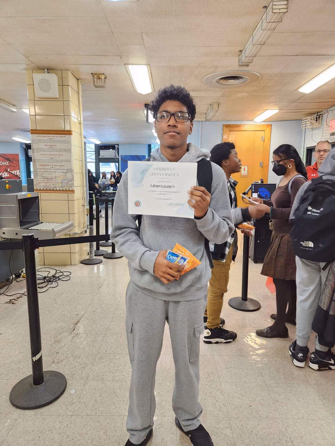 Student holding a perfect attendance certificate in school lobby