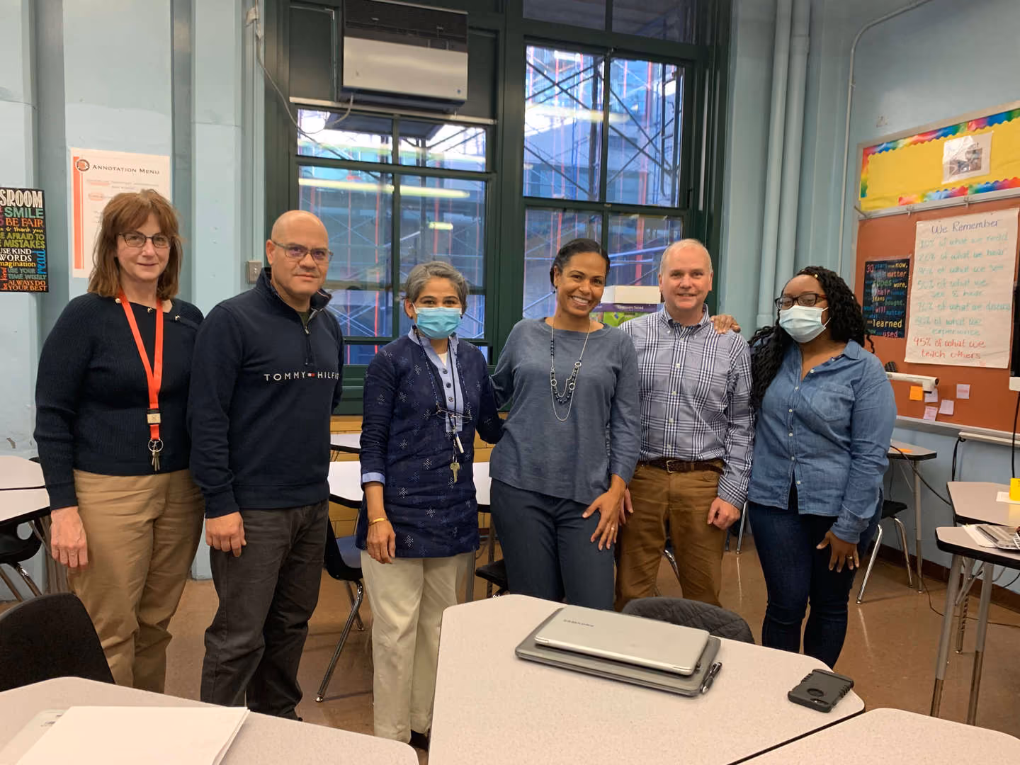 Six school staff members posing together in a classroom