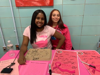 Two students at a breast cancer awareness event table
