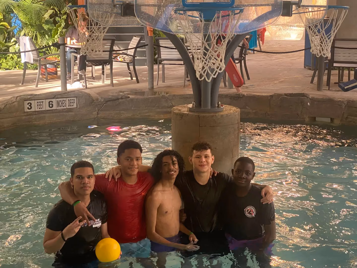 Five students posing together in indoor water park pool