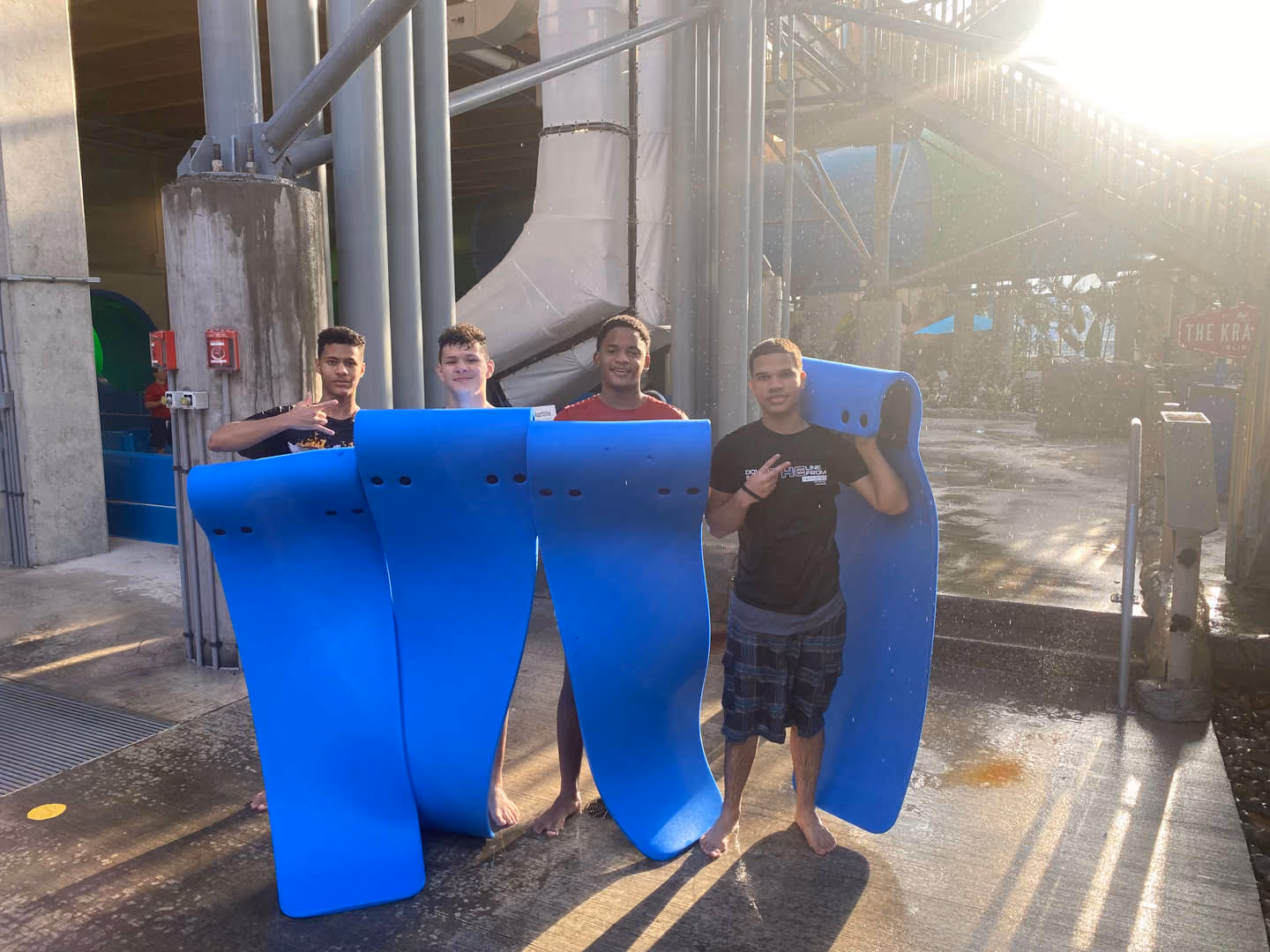 Four students holding blue water slides mats at indoor water park