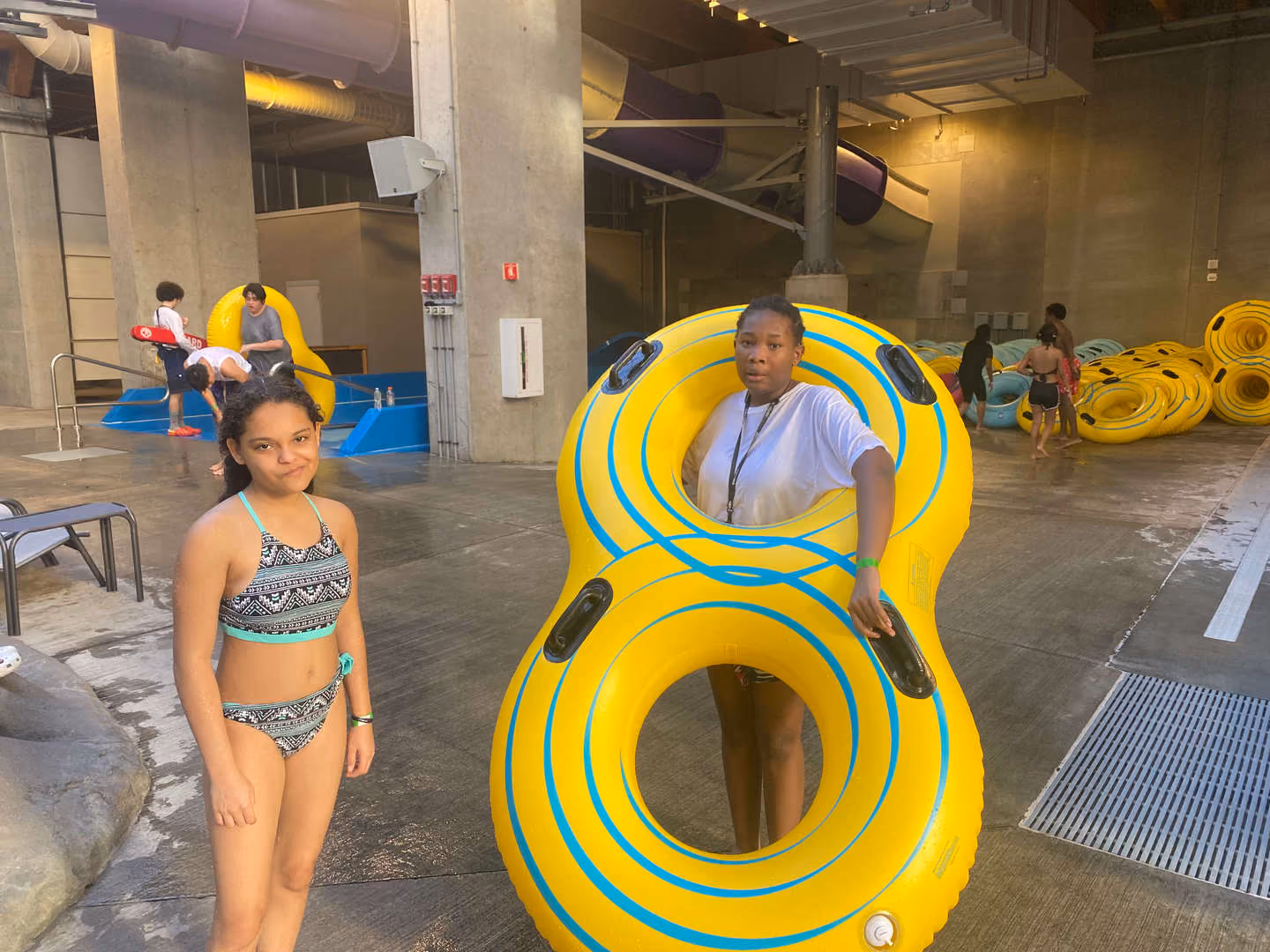 Two students posing with yellow inner tubes at indoor water park