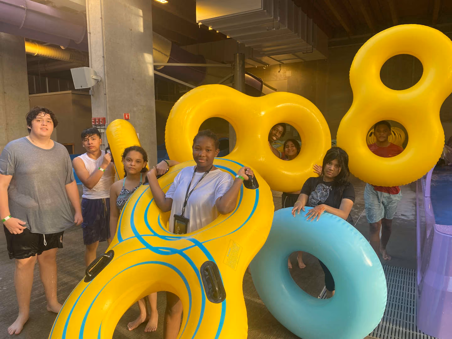 Students posing with colorful inflatable tubes at indoor water park