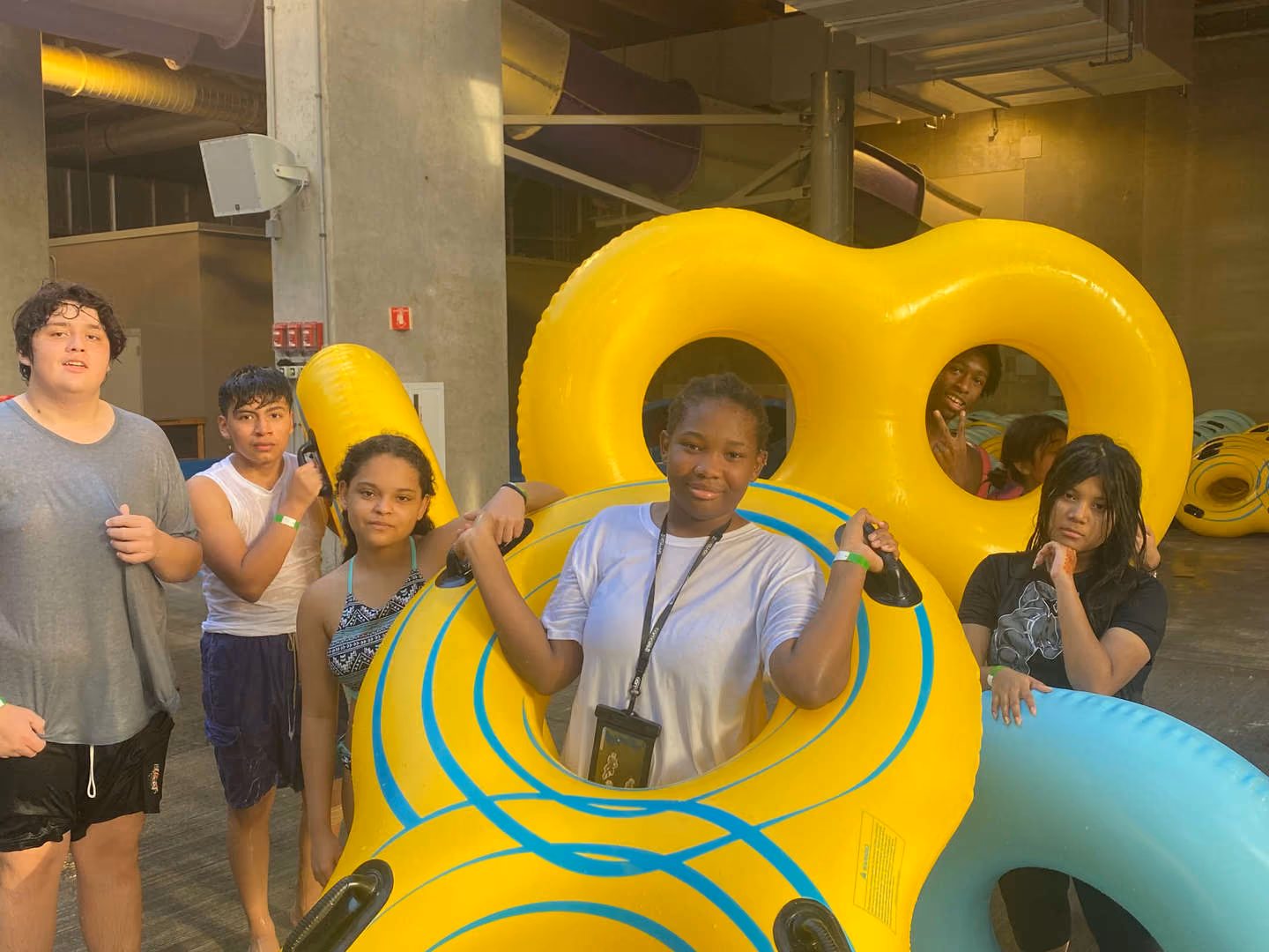 Students posing with large yellow inner tubes at indoor water park