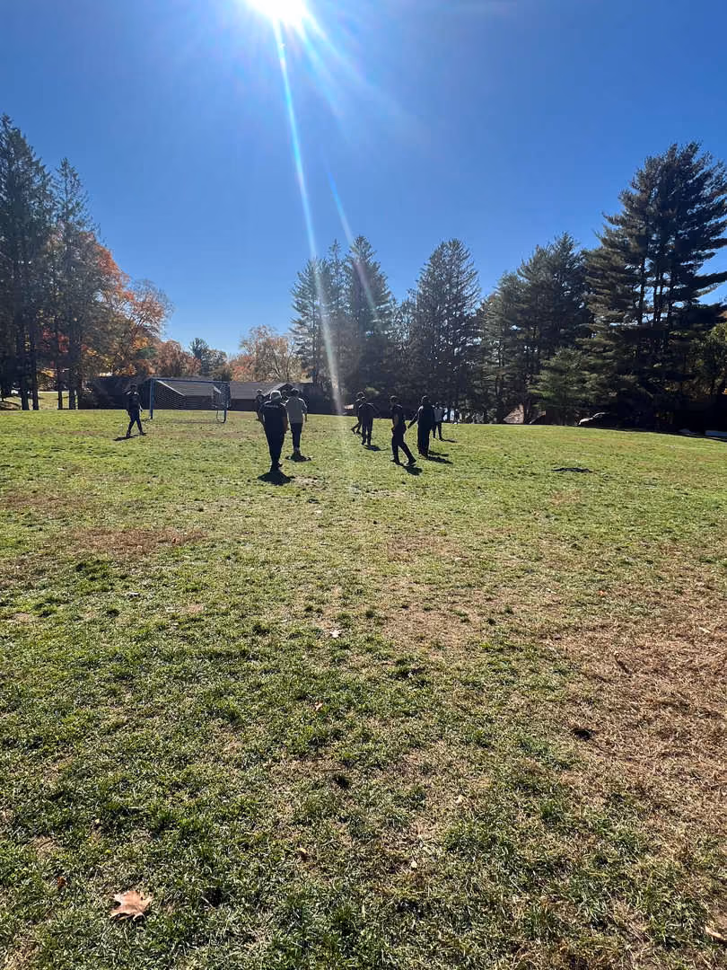 Students playing soccer on an outdoor field on a sunny fall day