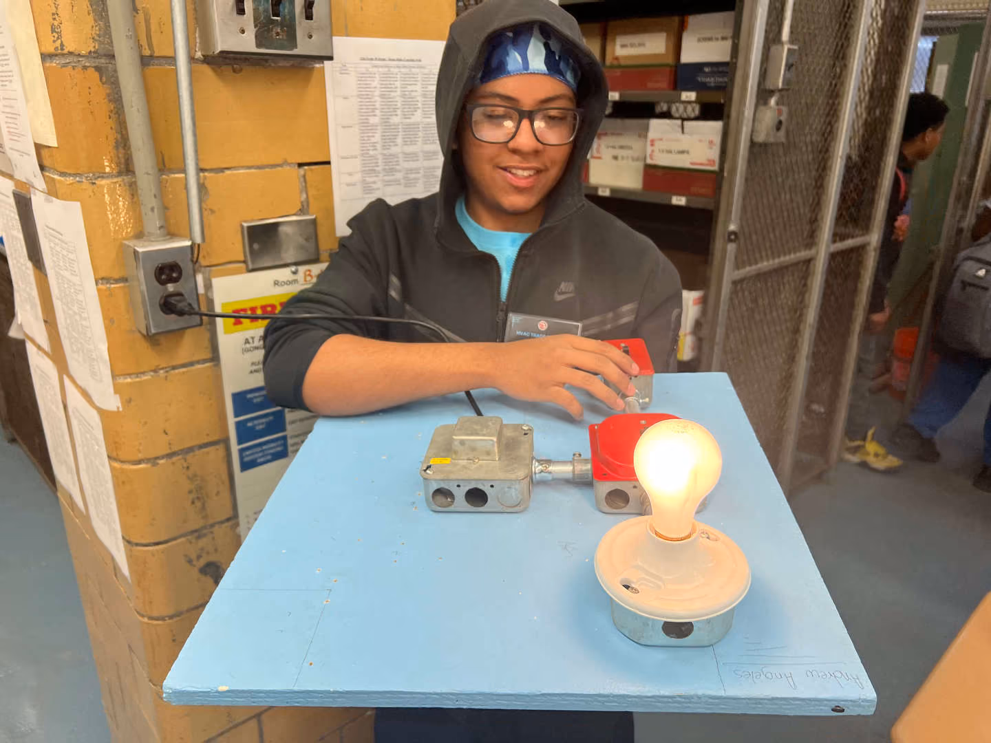 Student wiring an electrical circuit with a lit light bulb