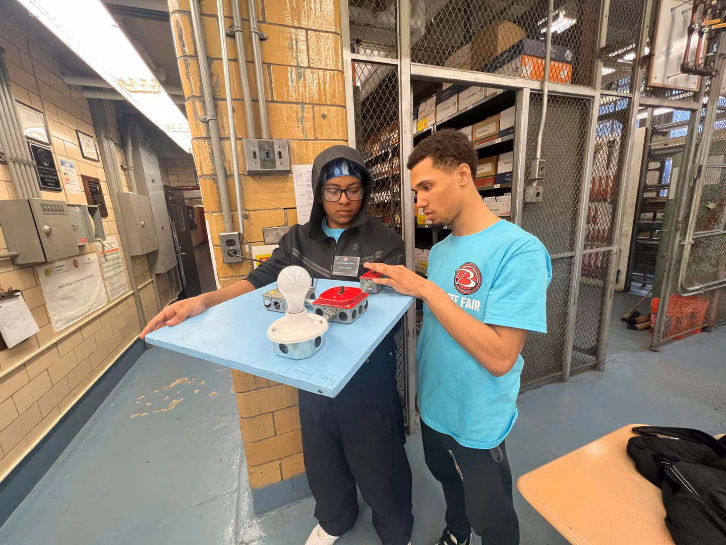 Two students examining electrical components on a board in shop class