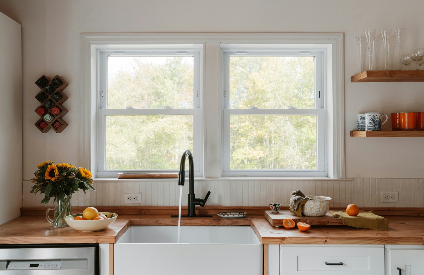 A bright kitchen with a wooden counter and a sink beneath two windows