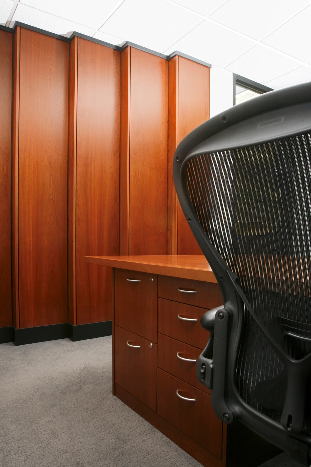 Black office chair faces a wooden desk