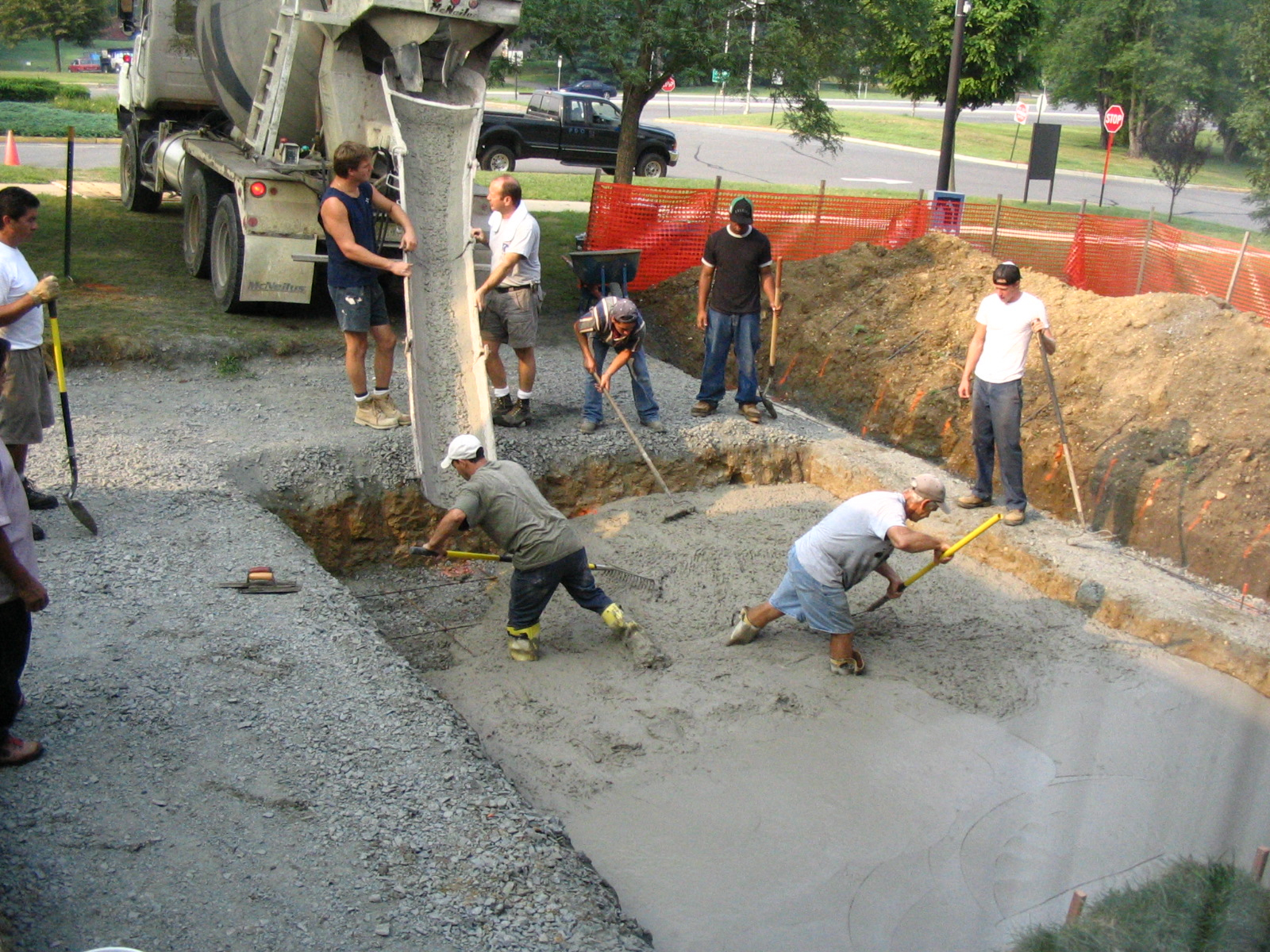 Construction workers pouring concrete into a foundation pit.