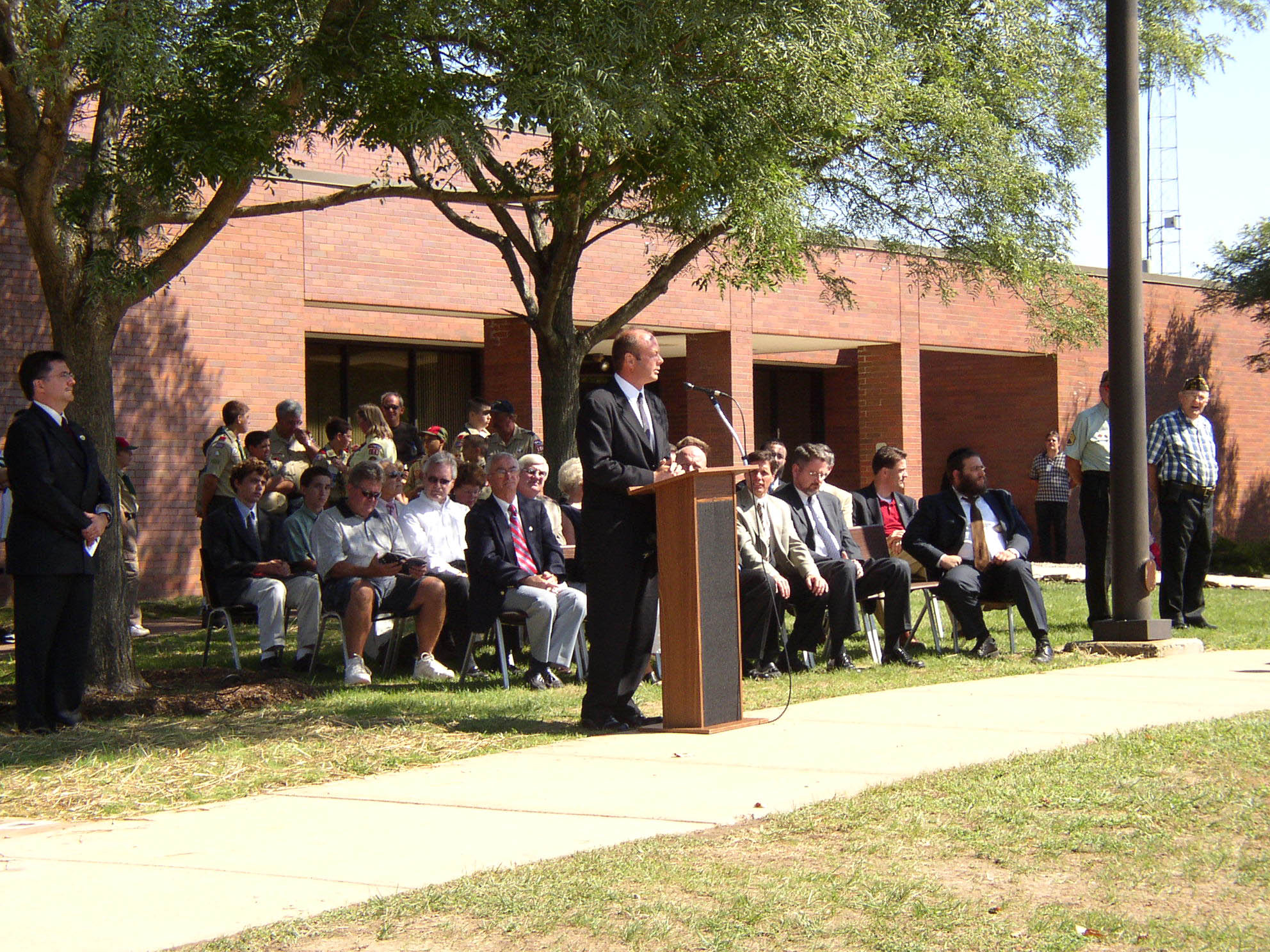 Speaker at an outdoor podium addressing an audience.