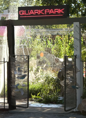 Garden entrance featuring a "QUARK PARK" neon sign under a wooden arbor.