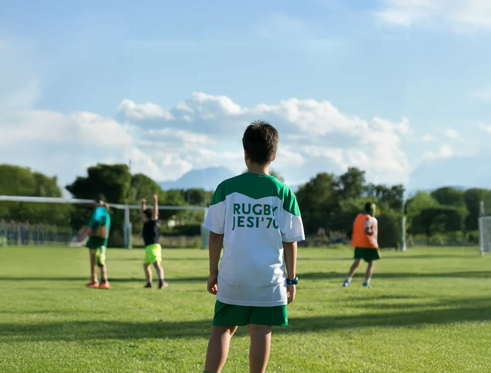 Un giovane giocatore del Rugby Jesi '70 guarda i compagni allenarsi in campo