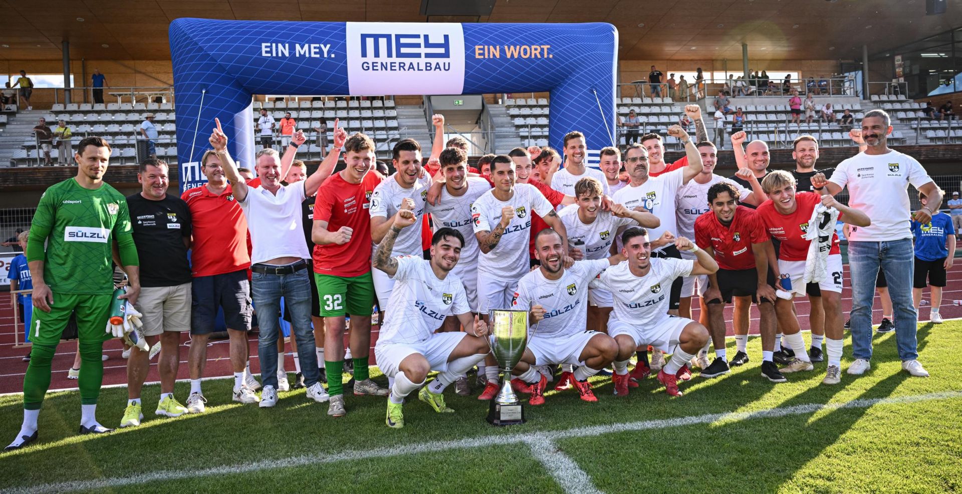 Fußballteams feiern unter dem Mey-Bogen beim Mey Generalbau Cup