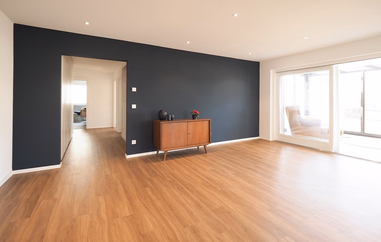 Renovierter Wohnraum mit Holzboden und dunkler Akzentwand