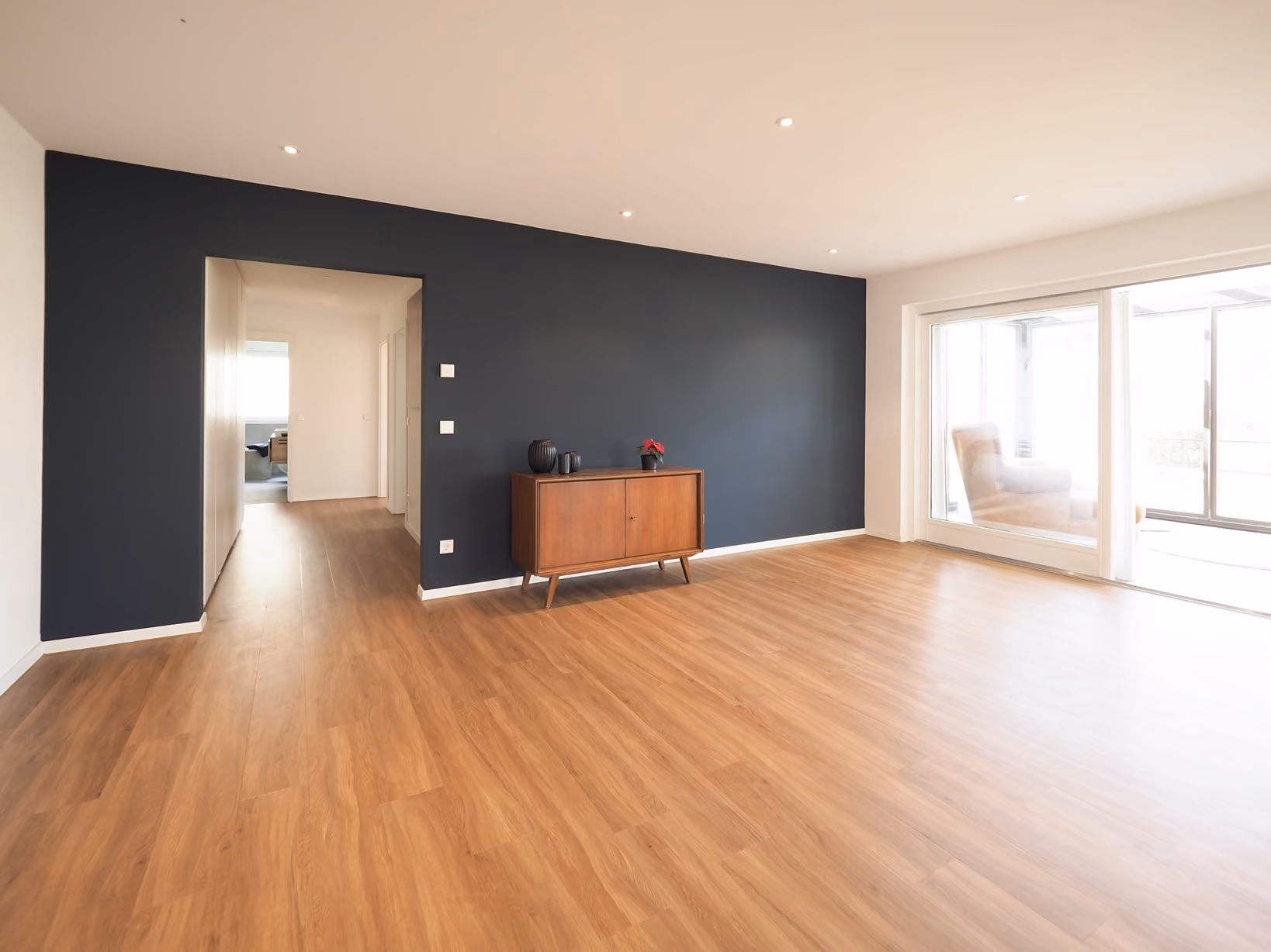 Modernisierter Wohnraum mit Holzboden und dunkler Akzentwand