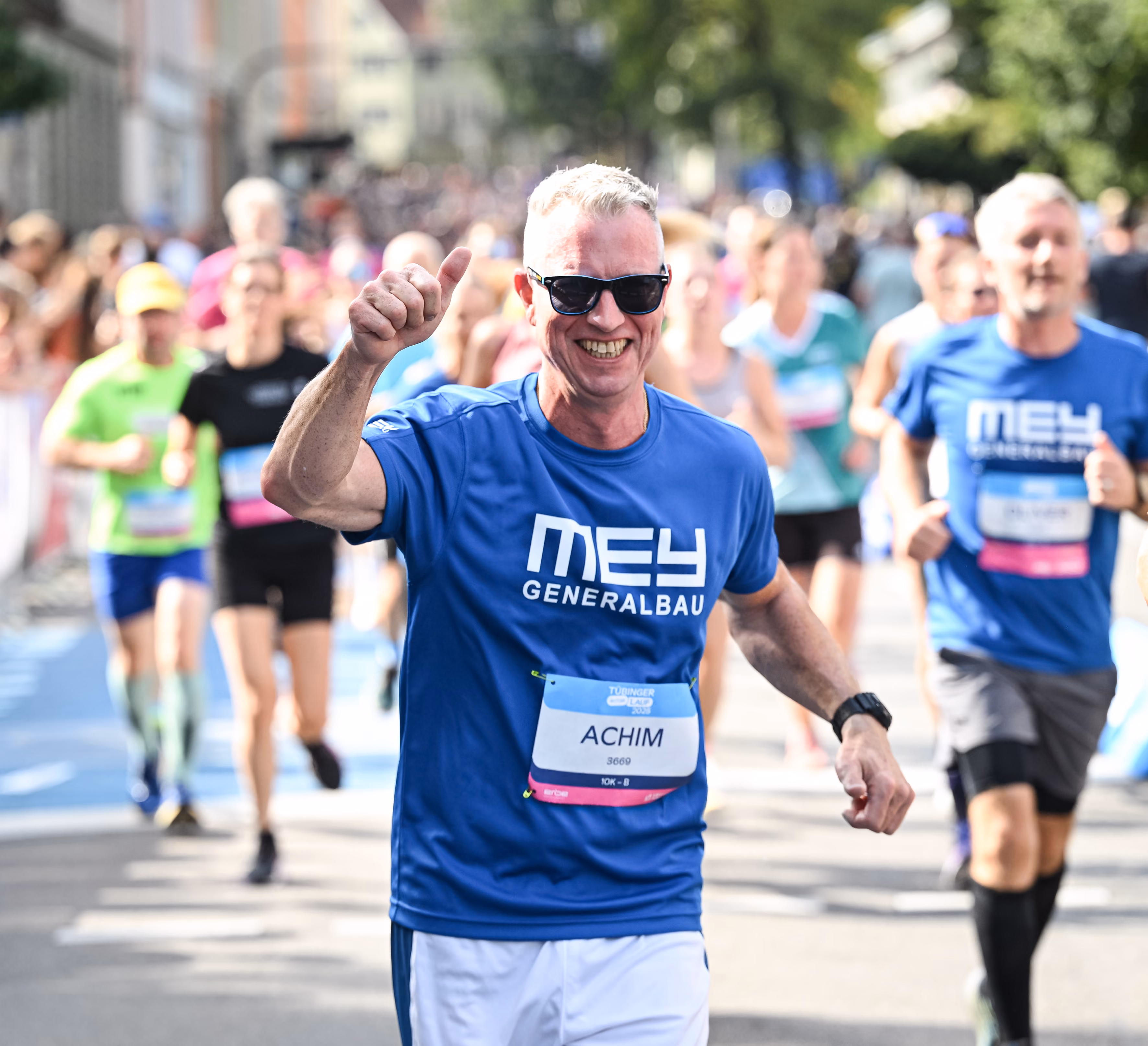 Läufer im Mey-Shirt winkt beim ERBE-Lauf Tübingen