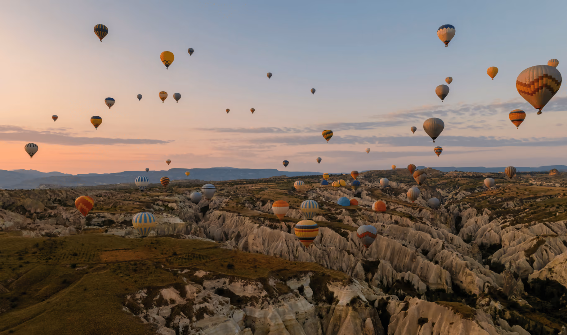Hot air balloons drifting over the valleys of Cappadocia at sunrise