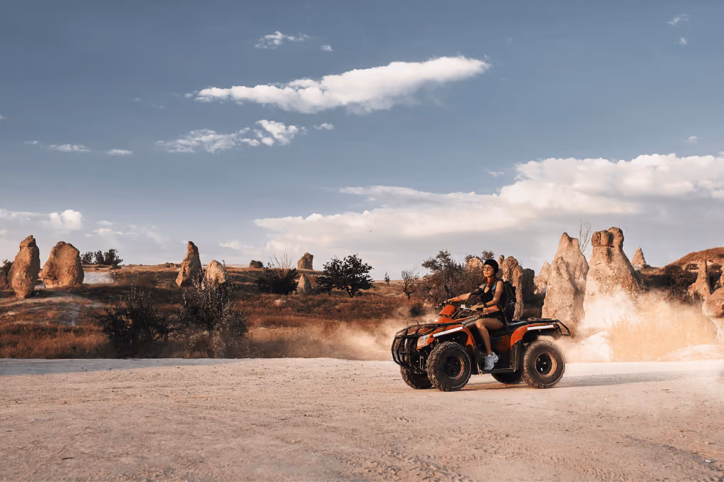 Quad bike kicking up dust among the rock formations of Cappadocia