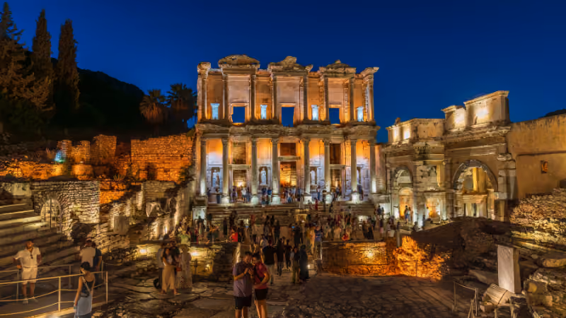 Library of Celsus in Ephesus illuminated at night with visitors in front