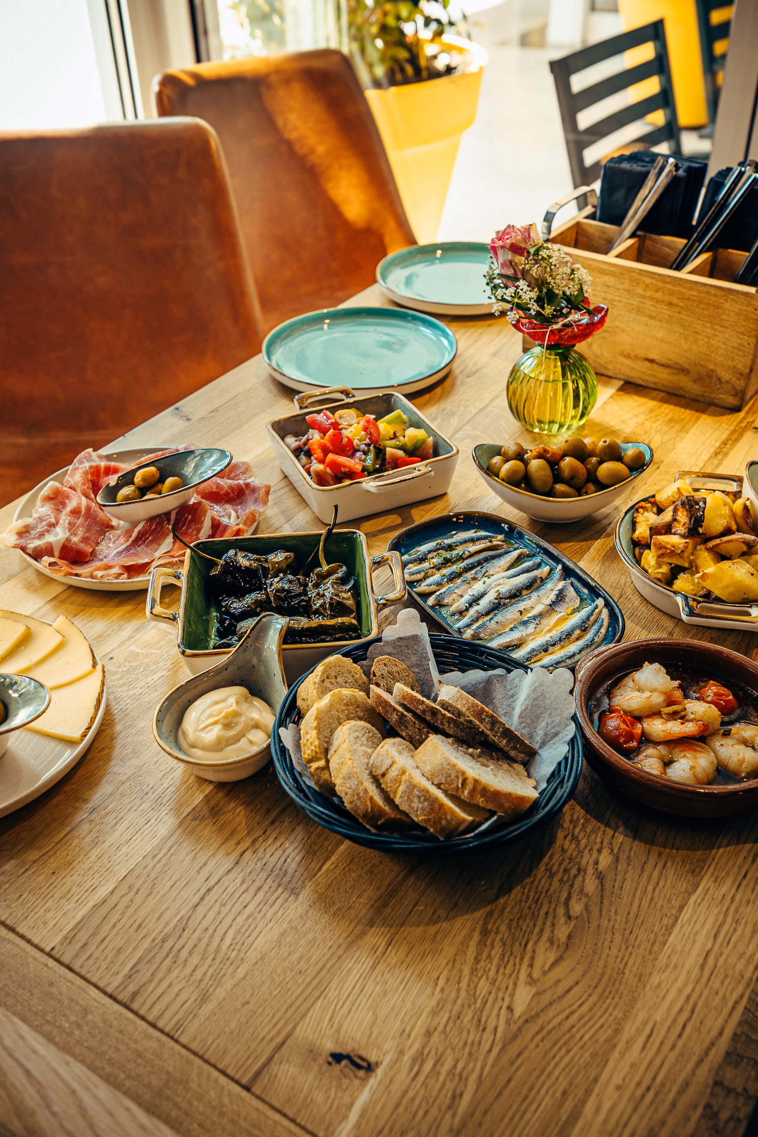 Holztisch mit verschiedenen Tapas-Schalen und Getränken