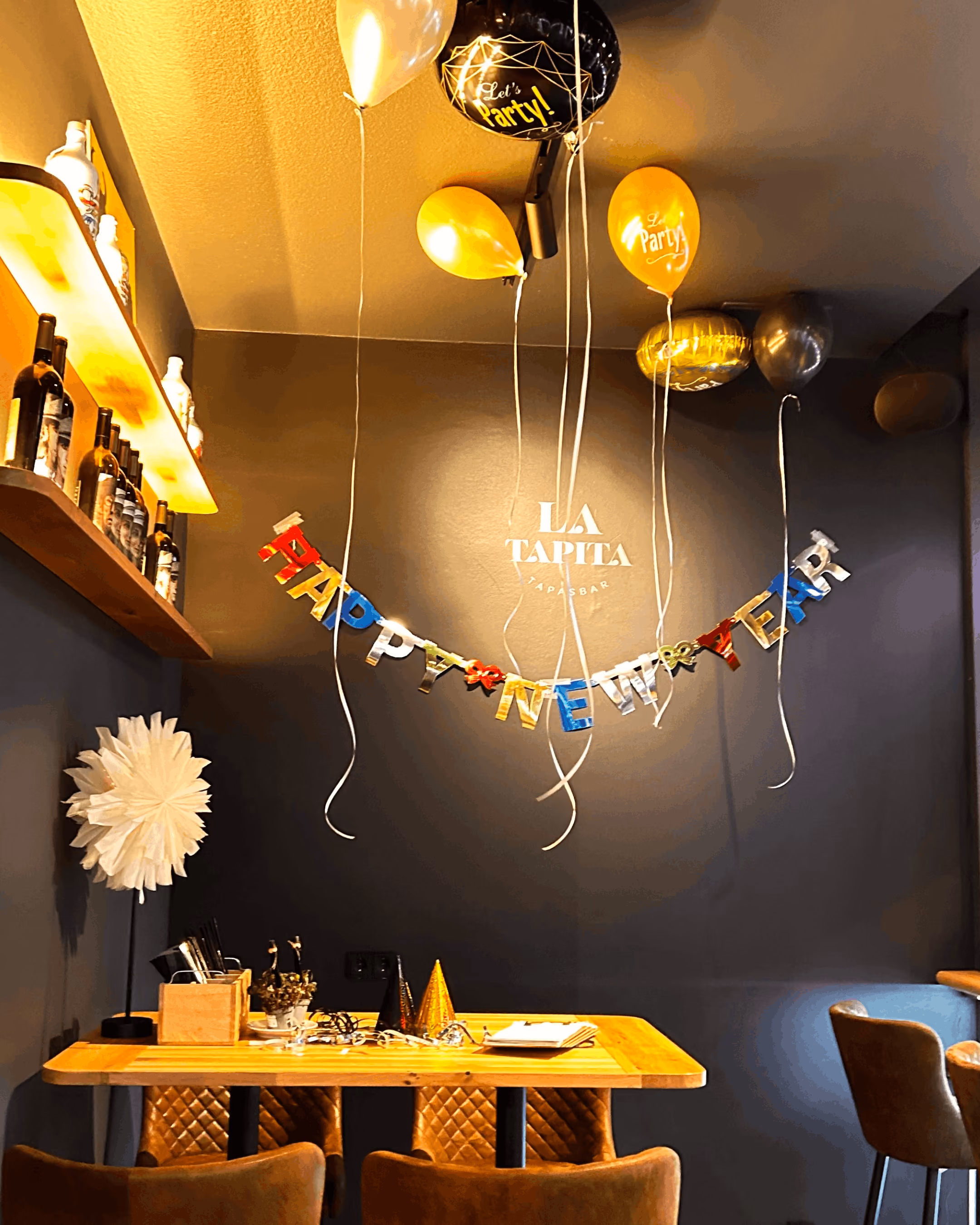 LaTapita-Logowand mit Silvester-Dekoration, Ballons und „Happy New Year“-Girlande