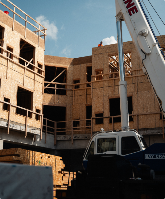 Timber-framed building under construction with a crane.