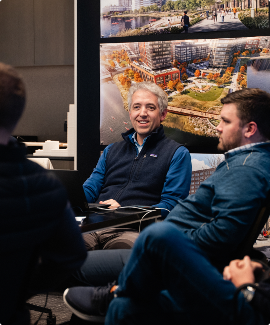 Design team meeting around architectural render boards.
