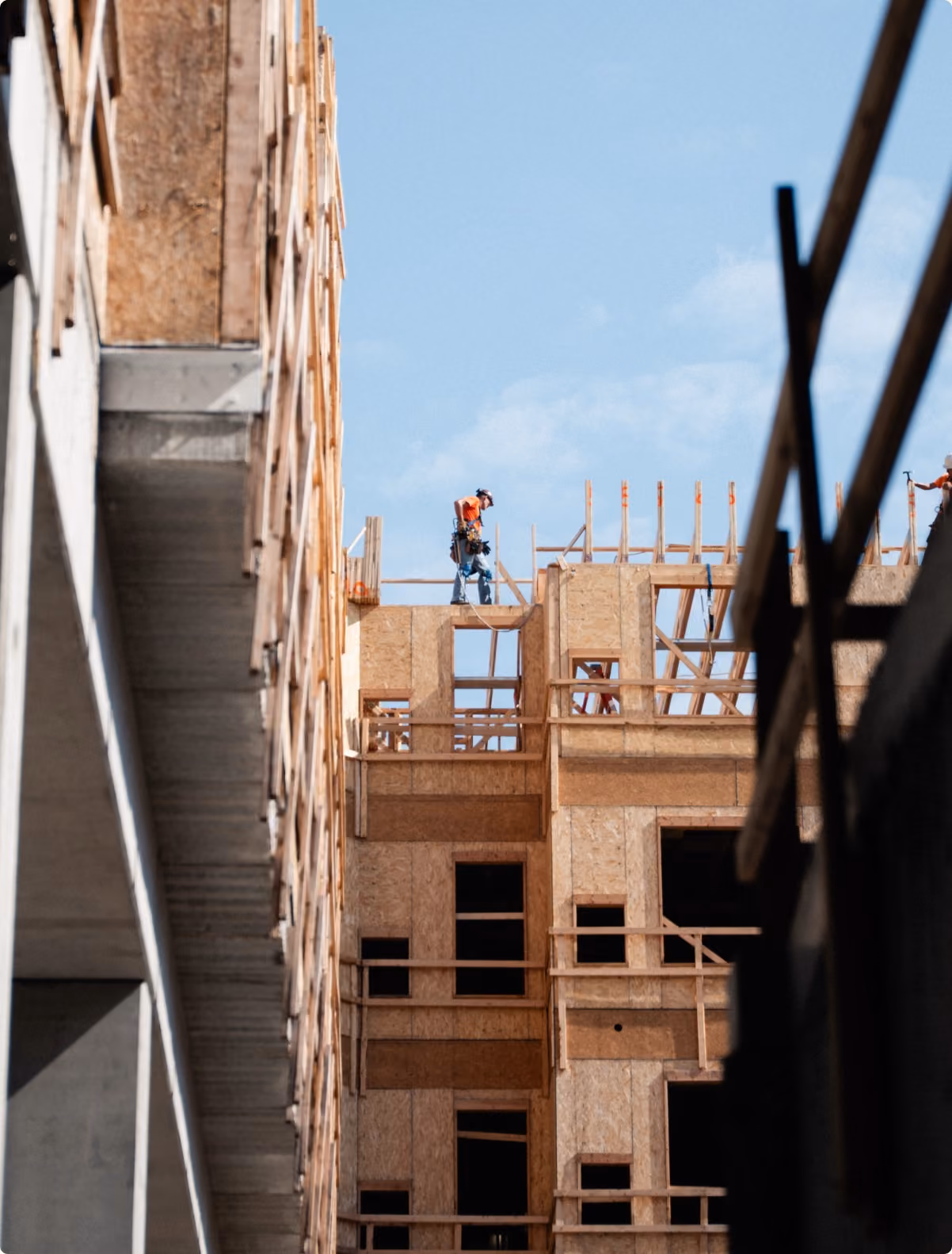 Crew working on the upper framing of a multi-story building, seen from a concrete stairwell