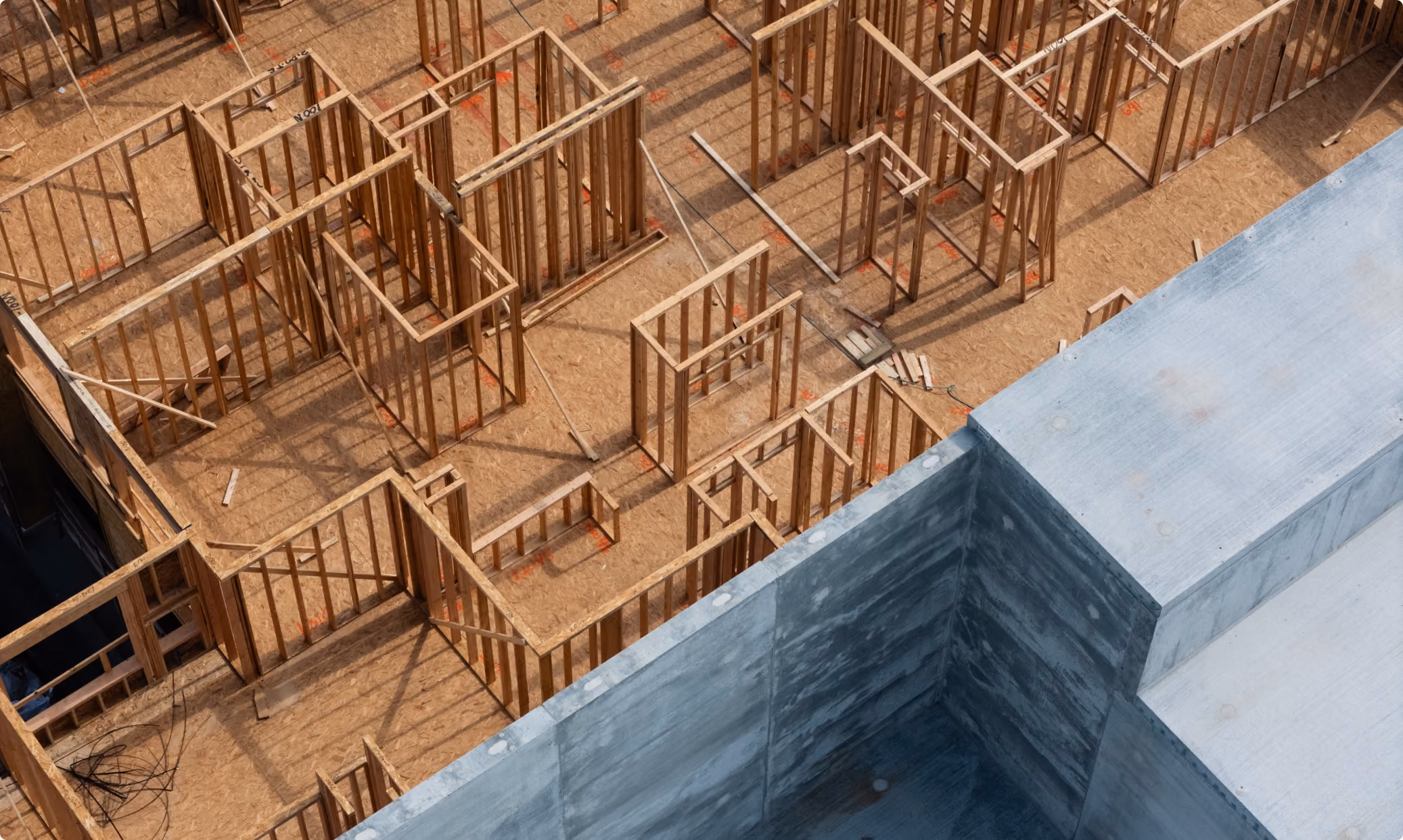 Construction worker walking through a sunlit unfinished interior.