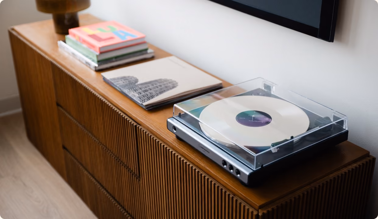 Record player and art books styled on a fluted wood sideboard in a finished interior