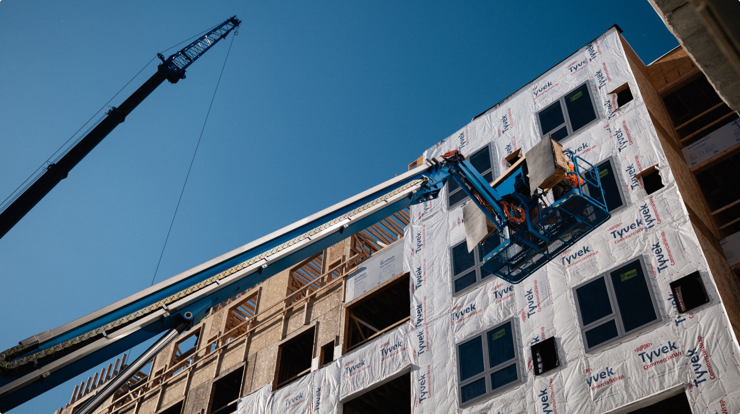 Tower crane above the Residences at Eastbank facade during construction.