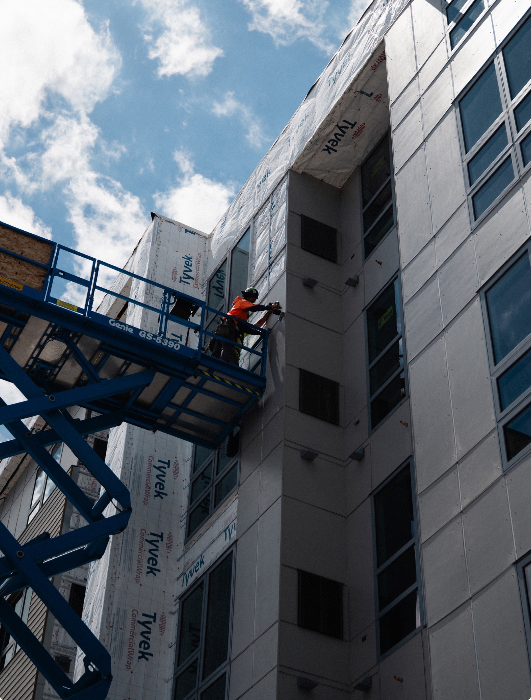Boom lift along the Residences at Eastbank facade during exterior work.