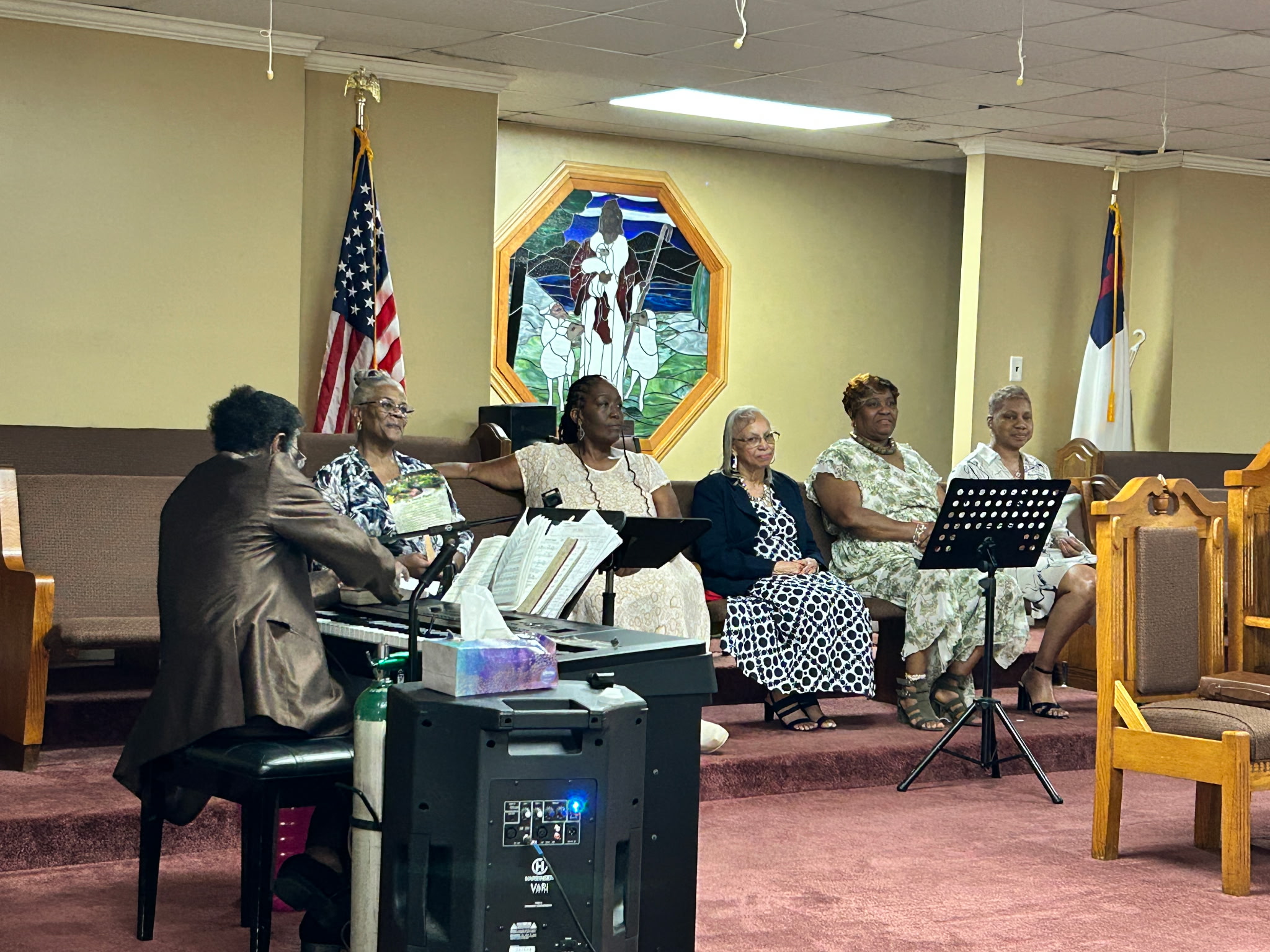 Women of the congregation seated in the pulpit while the musician plays during service