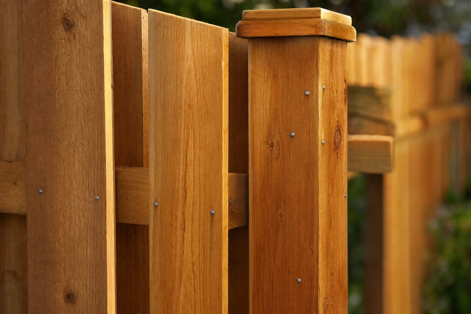 Close-up of overlapping cedar pickets and a 4x4 post on a board-on-board privacy fence