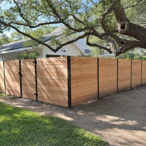 Modern horizontal cedar fence with exposed black steel posts at a backyard corner in Houston, TX