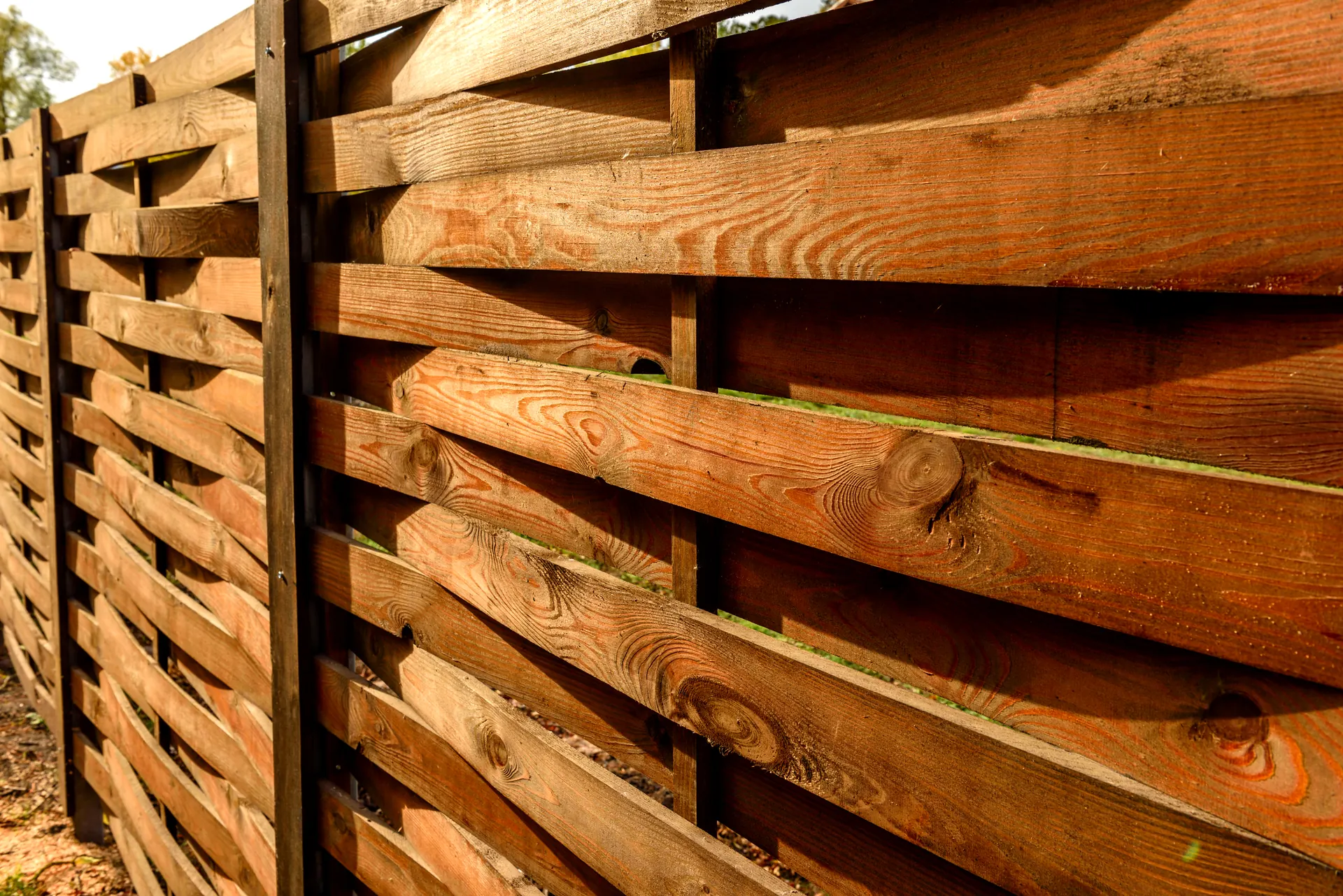 Close-up of a modern horizontal wood plank fence lit by afternoon sun